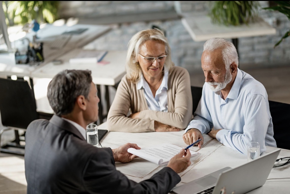 An adviser reviewing documents with a couple across a meeting table